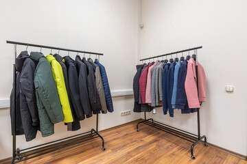 Hangers with outerwear in a modern showroom.