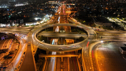 Fototapeta na wymiar Aerial drone slow shutter night photo of illuminated urban elevated toll ring road junction and interchange overpass passing through Kifisias Avenue, Attica, Greece