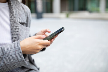 Unrecognizable businesswoman using smartphone typing on device outdoors