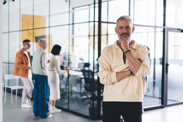 Thoughtful mature man looking at camera in contemporary spacious workspace