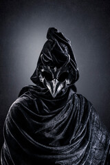 Fototapeta na wymiar Creepy figure with animal horned skull over dark misty background