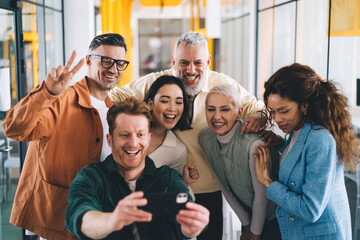 Joyful diverse coworkers taking self portrait in office
