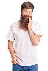 Handsome young red head man with long beard wearing casual white tshirt touching mouth with hand with painful expression because of toothache or dental illness on teeth. dentist