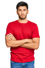 Obraz premium Young handsome man wearing casual red tshirt skeptic and nervous, disapproving expression on face with crossed arms. negative person.