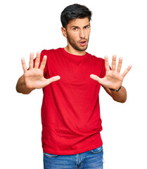 Fototapeta premium Young handsome man wearing casual red tshirt doing stop gesture with hands palms, angry and frustration expression
