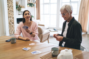 Happy diverse women playing cards in light apartment