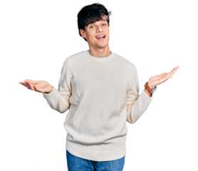 Handsome hipster young man wearing casual winter sweater clueless and confused expression with arms and hands raised. doubt concept.