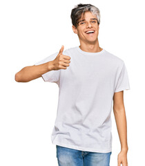 Young hispanic man wearing casual white tshirt smiling happy and positive, thumb up doing excellent and approval sign