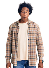 Handsome african american man with afro hair wearing casual clothes and glasses making fish face...