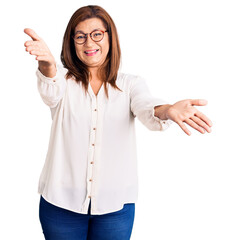Middle age latin woman wearing casual clothes and glasses looking at the camera smiling with open arms for hug. cheerful expression embracing happiness.