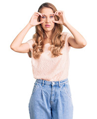 Young beautiful caucasian woman with blond hair wearing casual clothes trying to open eyes with fingers, sleepy and tired for morning fatigue