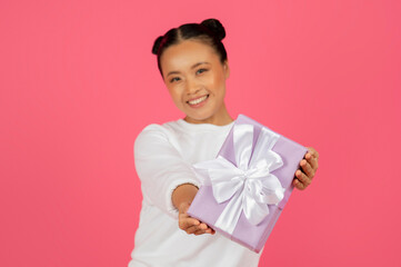 Happy young asian woman holding beautifully wrapped gift box