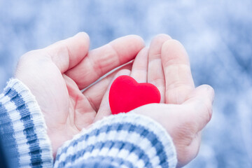 A In the hands of the heart in winter on the road in the park travel background