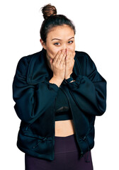 Obraz na płótnie Canvas Young hispanic girl wearing sportswear laughing and embarrassed giggle covering mouth with hands, gossip and scandal concept