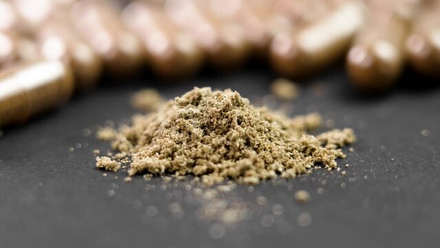 Supplement brown plant capsules and powder on black surface. Herbal medicinal product. Rotation. Macro shot
