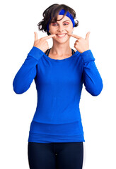 Obraz na płótnie Canvas Beautiful young woman with short hair wearing training workout clothes smiling cheerful showing and pointing with fingers teeth and mouth. dental health concept.