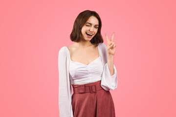 A spirited young woman winks and flashes a peace sign