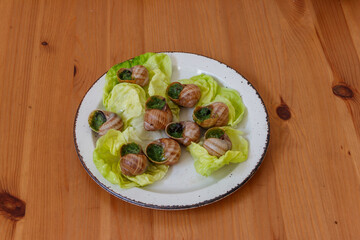 Escargots de Bourgogne (snails) seasoned with butter, parsley, garlic on wooden table