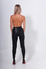 Topless blonde woman in leather pants from back full length