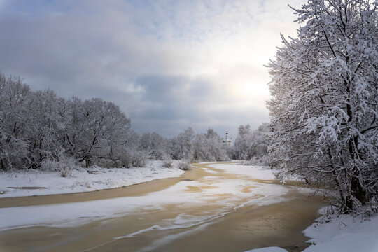 Winter landscape, a river covered with ice and snow, a beautiful sky with clouds against the background of white snow and a frozen river