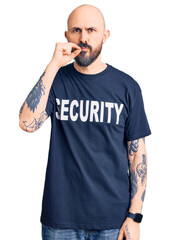 Young handsome man wearing security t shirt mouth and lips shut as zip with fingers. secret and...