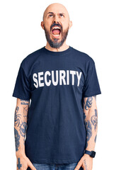 Young handsome man wearing security t shirt angry and mad screaming frustrated and furious, shouting with anger. rage and aggressive concept.