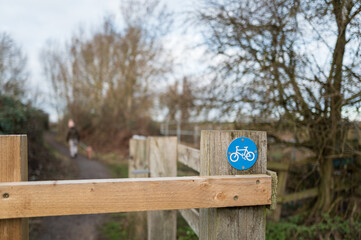 Shallow focus of an authorised blue cycle path sign attached to a wooden turnstile within a nature...