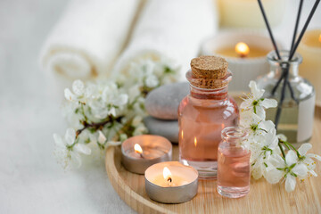 Aromatherapy, home decor concept. Glass perfume bottle, elegant composition with spring flowers. Burning candles, spa setting, essential oils, organic pure aromatic ingredients, atmosphere of relax