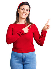 Young beautiful woman wearing casual clothes smiling and looking at the camera pointing with two hands and fingers to the side.