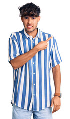 Young hispanic man wearing casual clothes pointing aside worried and nervous with forefinger,...