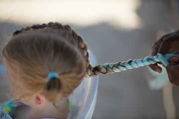 holding braids with pink color on little kid head. stylist applying braiding hair on young baby. - obrazy, fototapety, plakaty