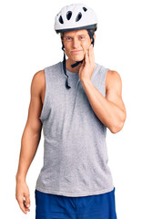 Young handsome man wearing bike helmet touching mouth with hand with painful expression because of toothache or dental illness on teeth. dentist