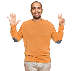 Fototapeta premium Hispanic adult man wearing casual winter sweater showing and pointing up with fingers number seven while smiling confident and happy.