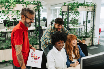 A cheerful interracial team solving problems with paperwork at office.
