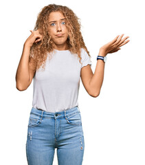 Beautiful caucasian teenager girl wearing casual white tshirt confused and annoyed with open palm showing copy space and pointing finger to forehead. think about it.
