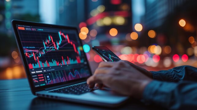 trader hand with mobile phone and computer screens with trading candlestick charts