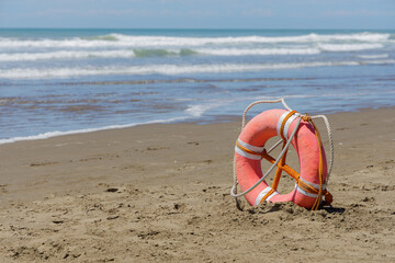 Lifebuoy on a deserted beach over blue sky.