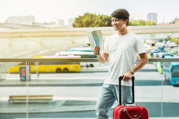 Young asian guy tourist checking paper map