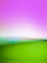 Spring fields with green grass and colorful bright sunset blurred texture