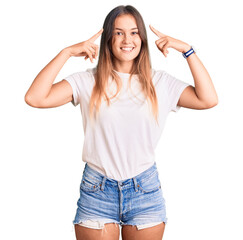 Obraz na płótnie Canvas Beautiful caucasian woman wearing casual white tshirt smiling pointing to head with both hands finger, great idea or thought, good memory
