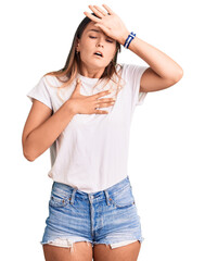 Beautiful caucasian woman wearing casual white tshirt touching forehead for illness and fever, flu and cold, virus sick