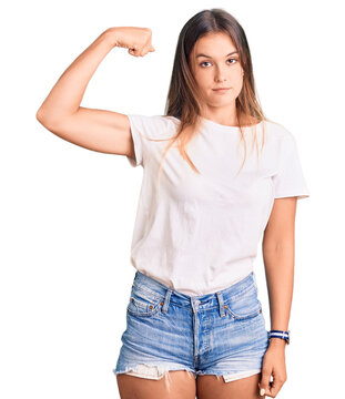 Beautiful caucasian woman wearing casual white tshirt strong person showing arm muscle, confident and proud of power