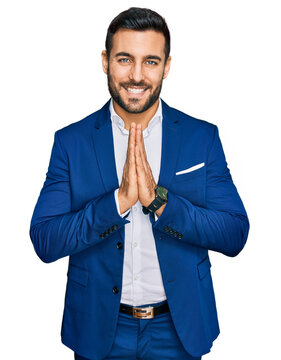 Young hispanic man wearing business jacket praying with hands together asking for forgiveness smiling confident.