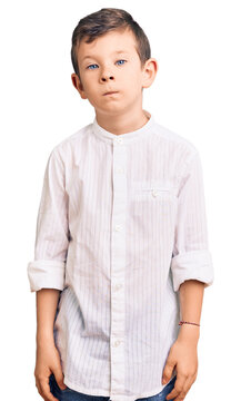 Cute blond kid wearing elegant shirt relaxed with serious expression on face. simple and natural looking at the camera.