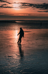 silhouette of a person iceskating on a frozen lake