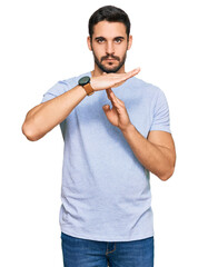Young hispanic man wearing casual clothes doing time out gesture with hands, frustrated and serious...