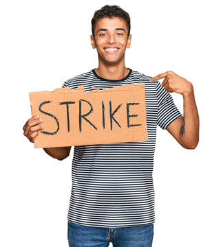 Young handsome african american man holding strike banner cardboard pointing finger to one self smiling happy and proud