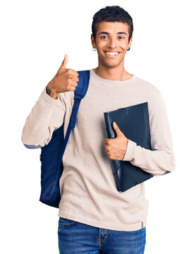 Young african amercian man wearing student backpack holding binder smiling happy and positive, thumb up doing excellent and approval sign