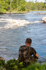 A man in nature takes pictures of himself on his phone. Relaxing in the forest by the river