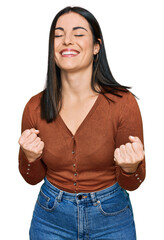 Young hispanic woman wearing casual clothes very happy and excited doing winner gesture with arms raised, smiling and screaming for success. celebration concept.